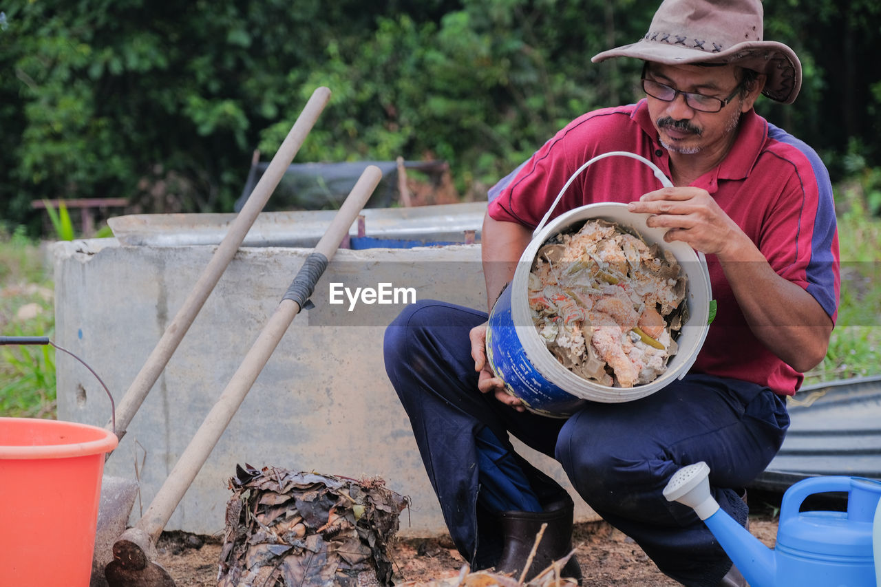 MIDSECTION OF MAN HOLDING FOOD WHILE SITTING ON BARBECUE