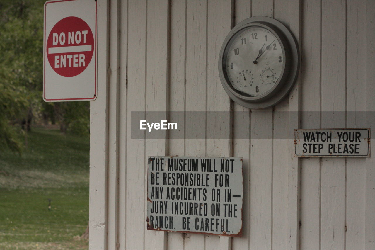 Warning signs and clock on wooden wall at ranch