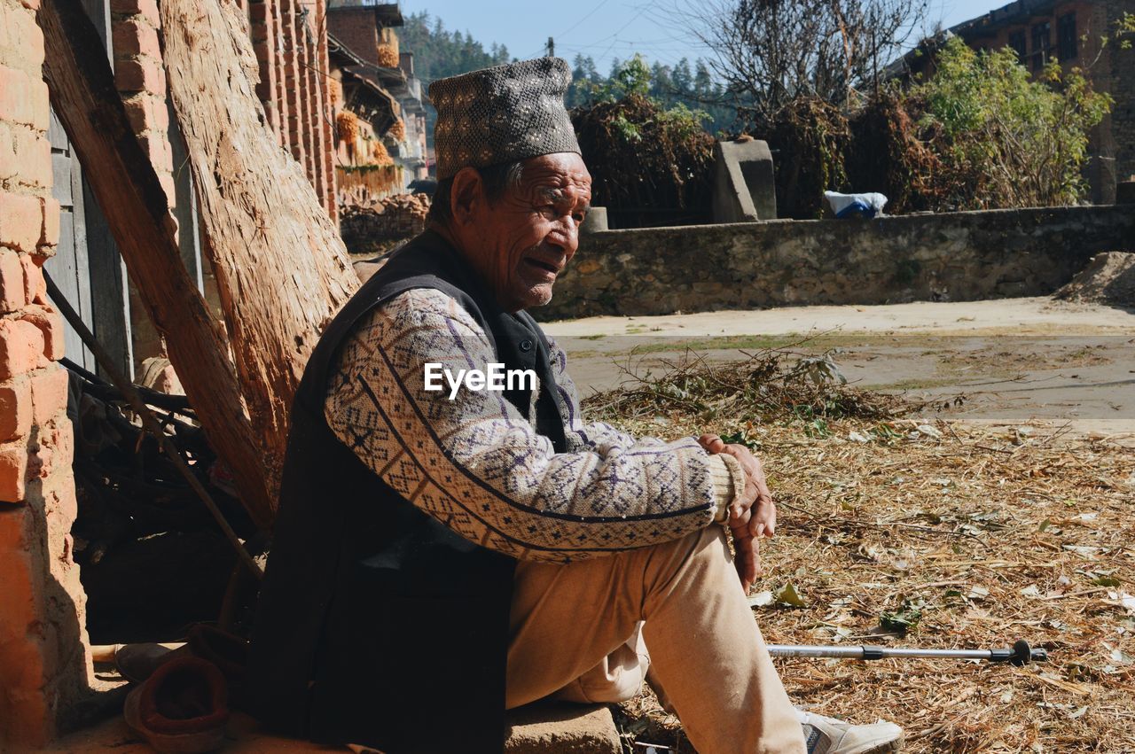 SIDE VIEW OF A MAN SITTING AT PARK