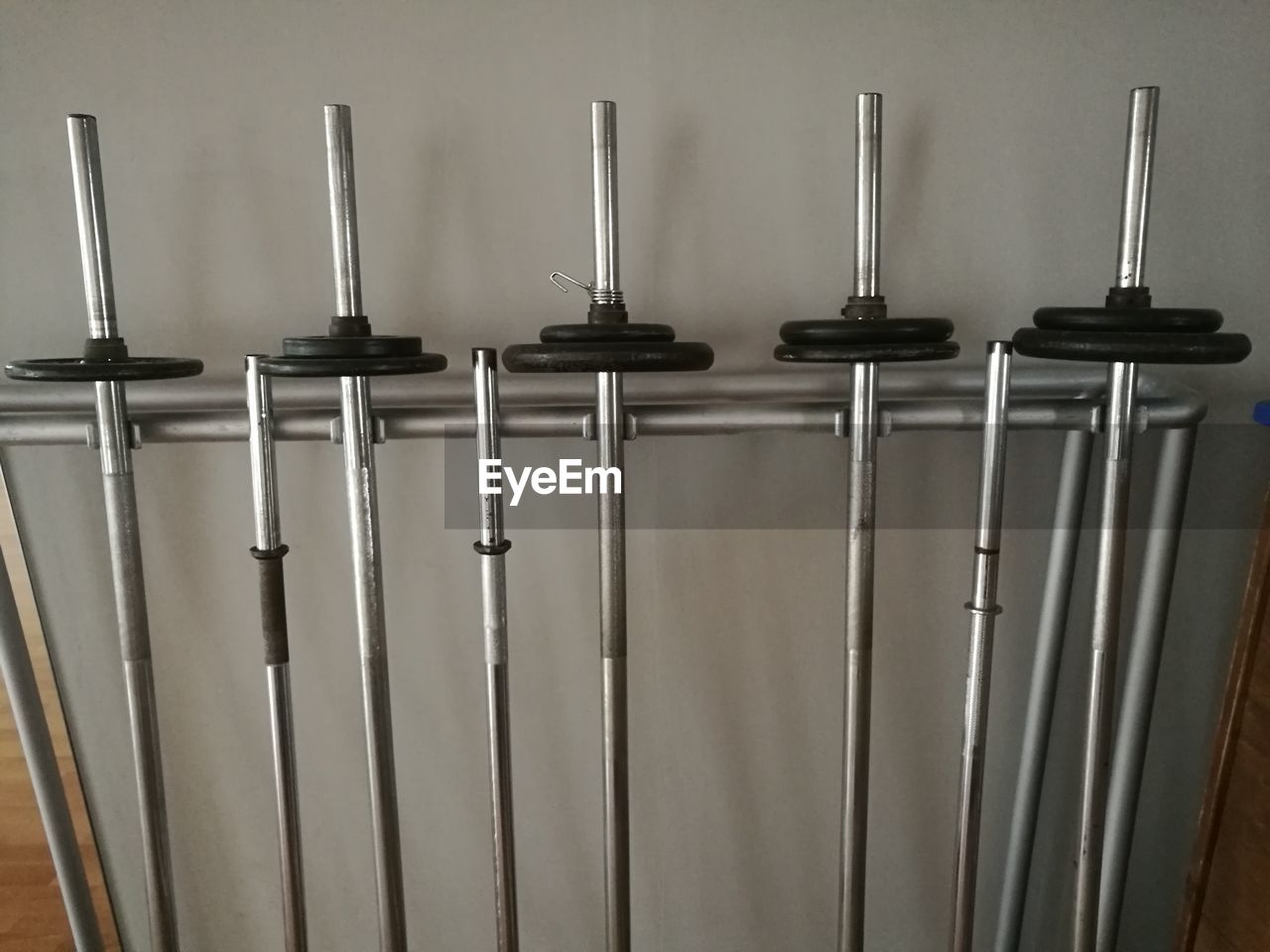 Barbells leaning on stand against wall in gym