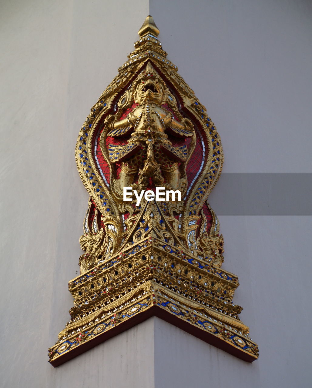 Low angle view of gold demon sculpture on wall