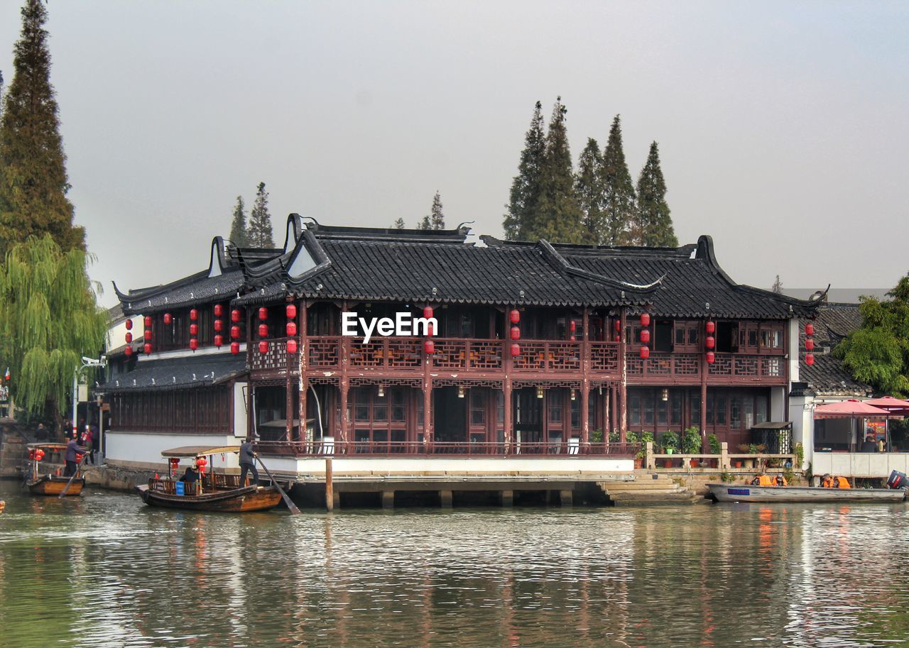 BOAT IN LAKE BY BUILDING AGAINST SKY