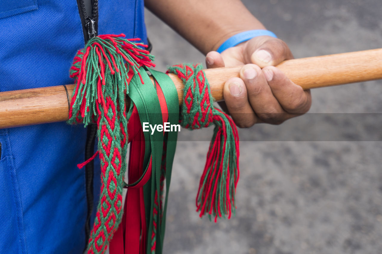 Midsection of person holding bamboo with ribbons