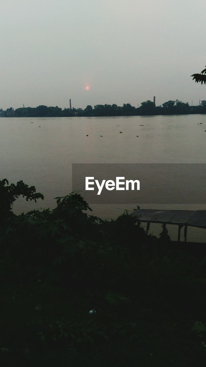 SILHOUETTE TREES BY RIVER AGAINST CLEAR SKY