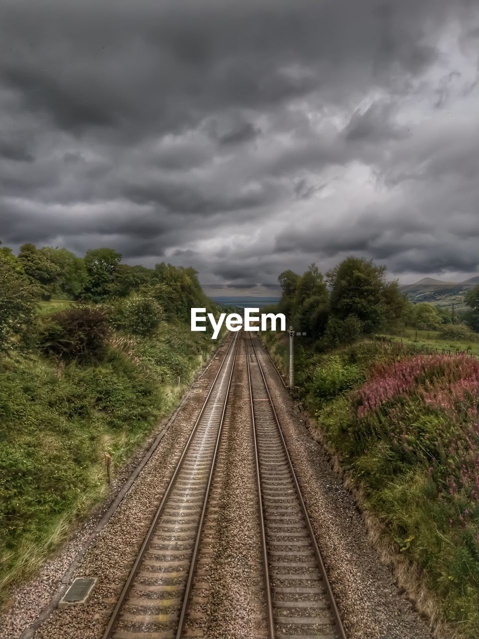 RAILROAD TRACKS AGAINST CLOUDY SKY