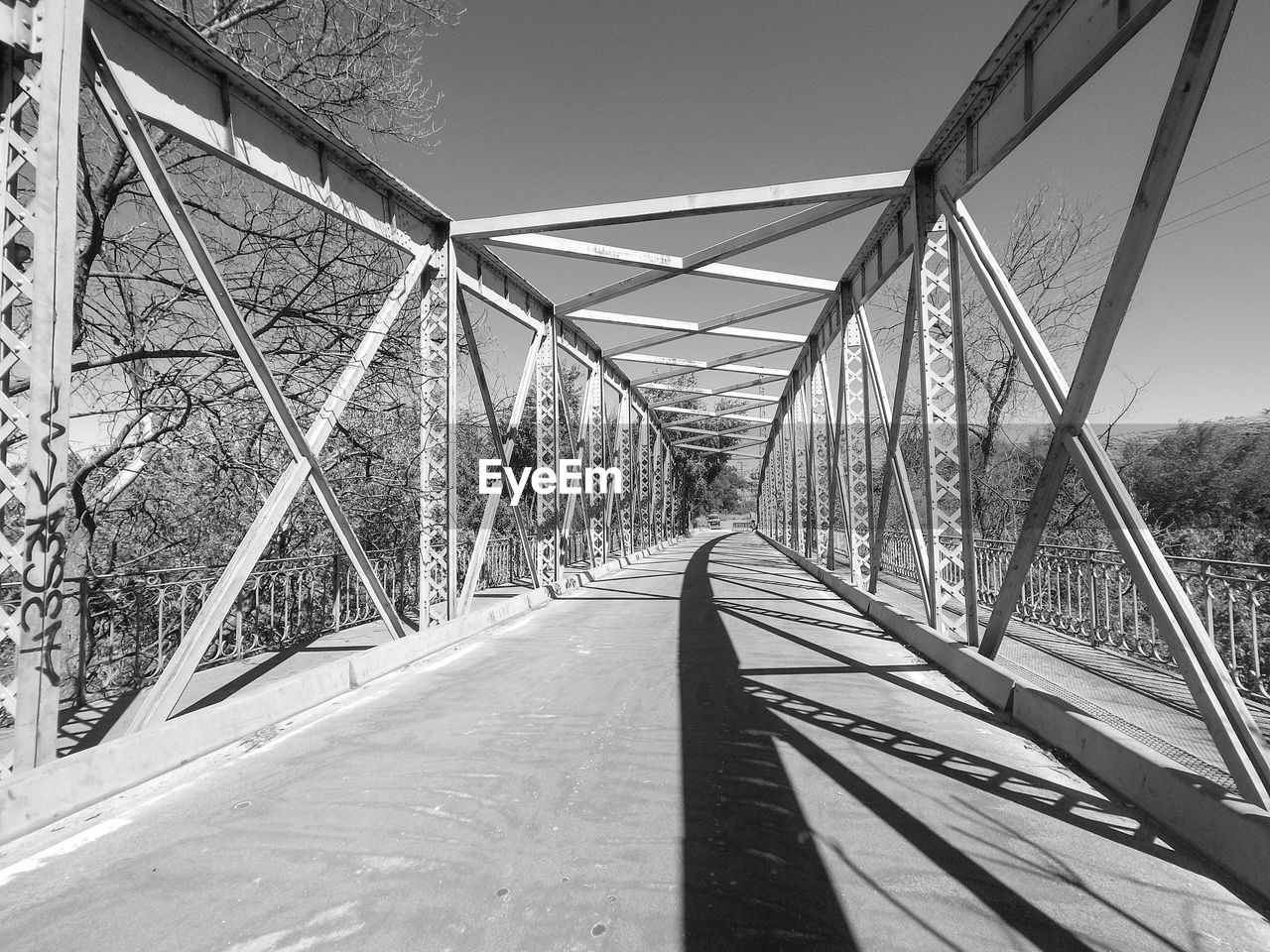 Black and white architecture photo of a metallic bridge over road, with clear sky. shot with sjcam