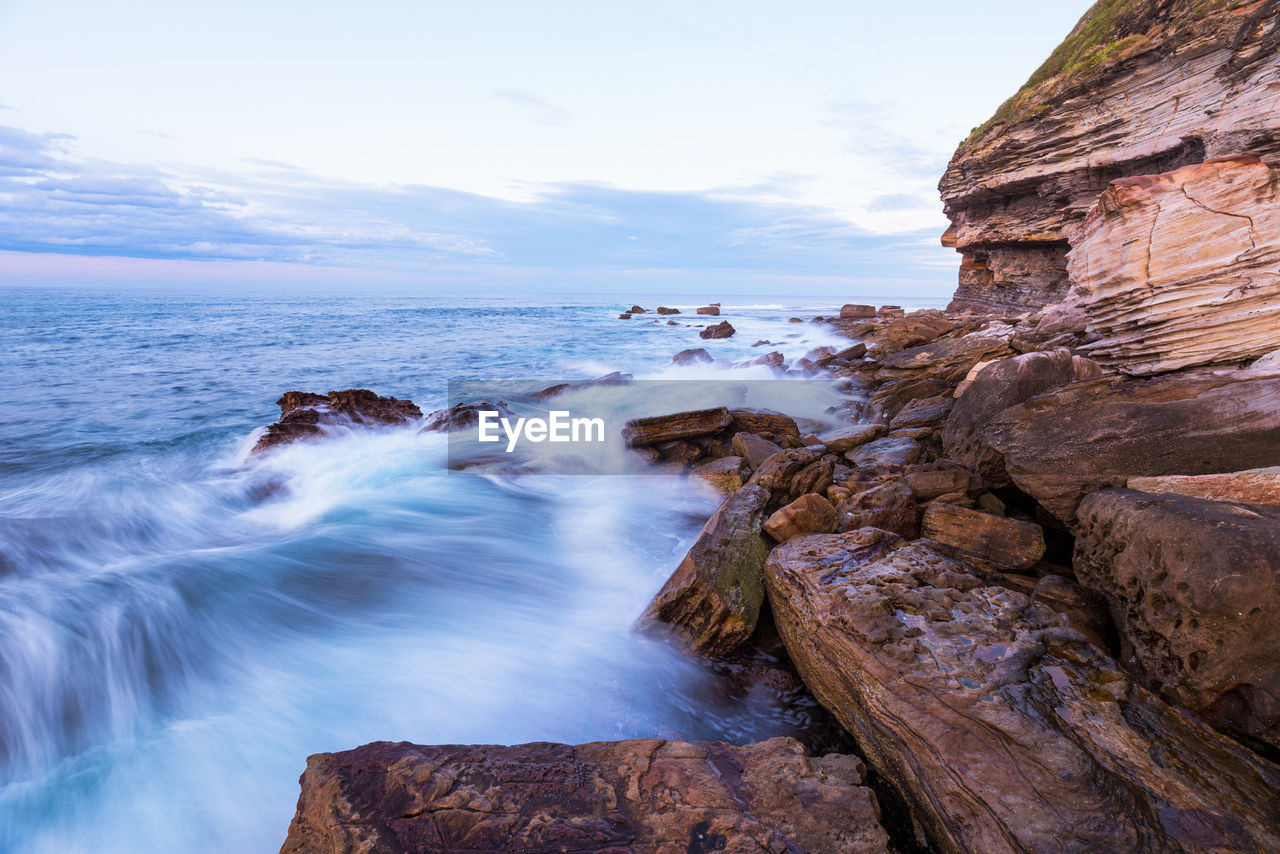 Scenic view of rocks in sea against sky