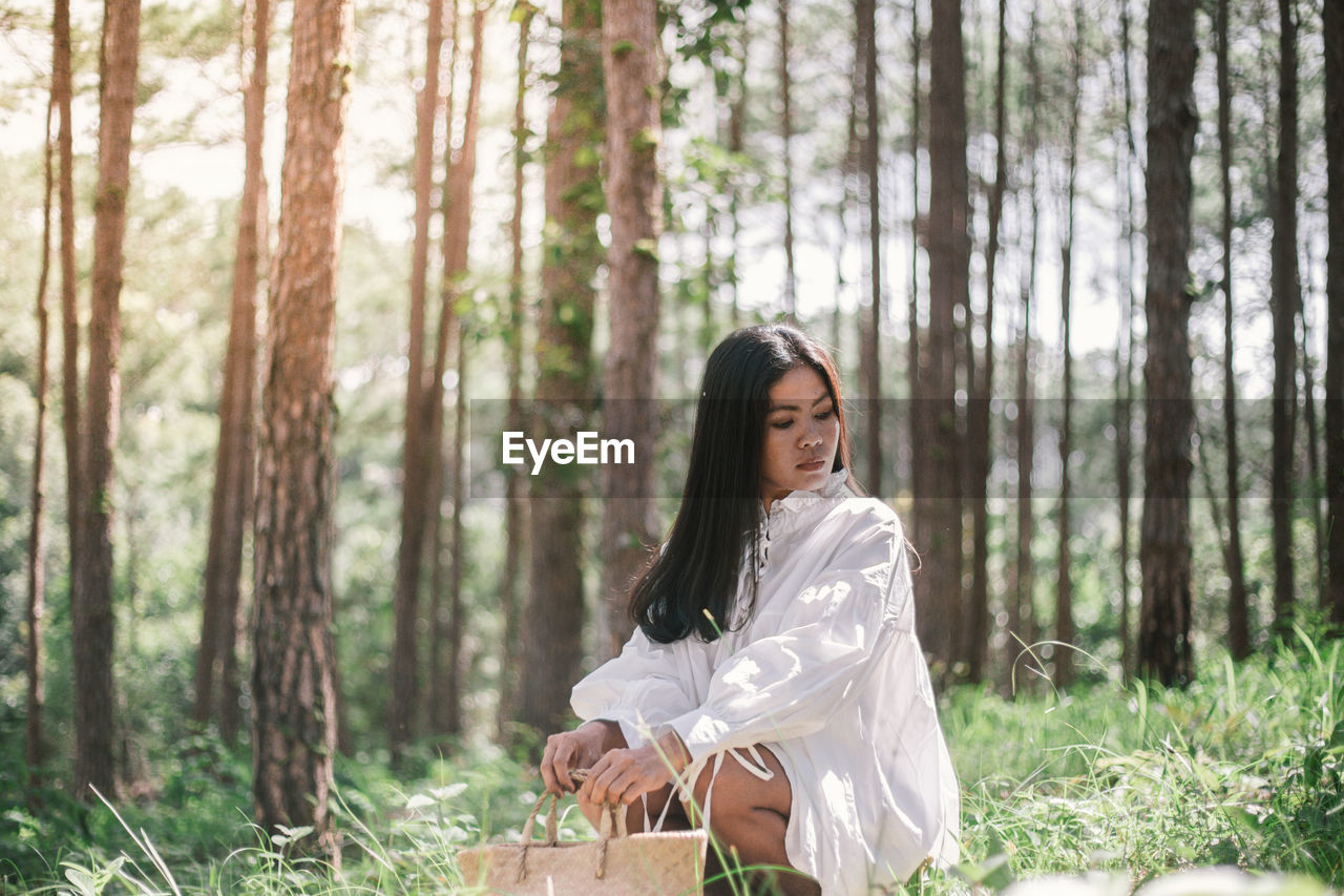 Woman crouching at forest