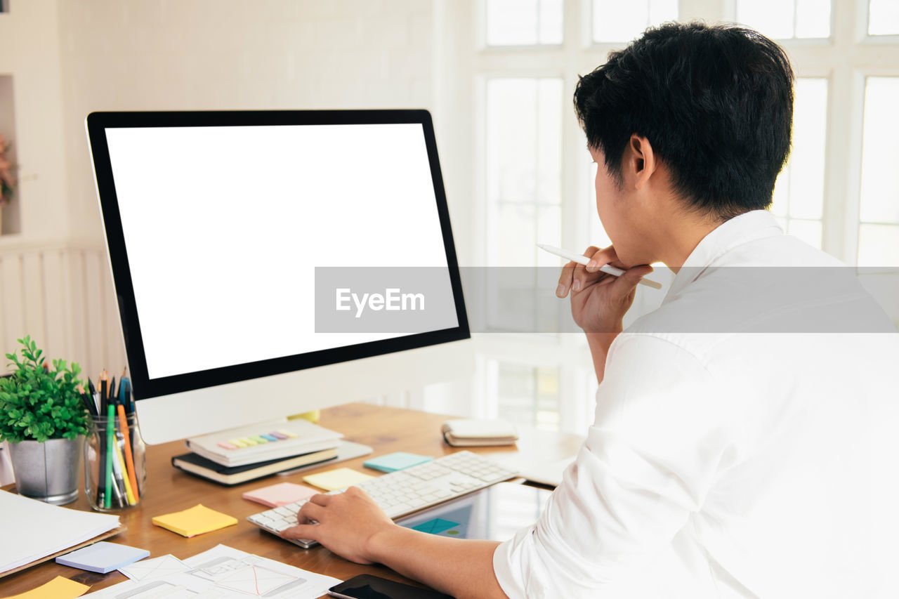 Side view of businessman using computer at desk in office