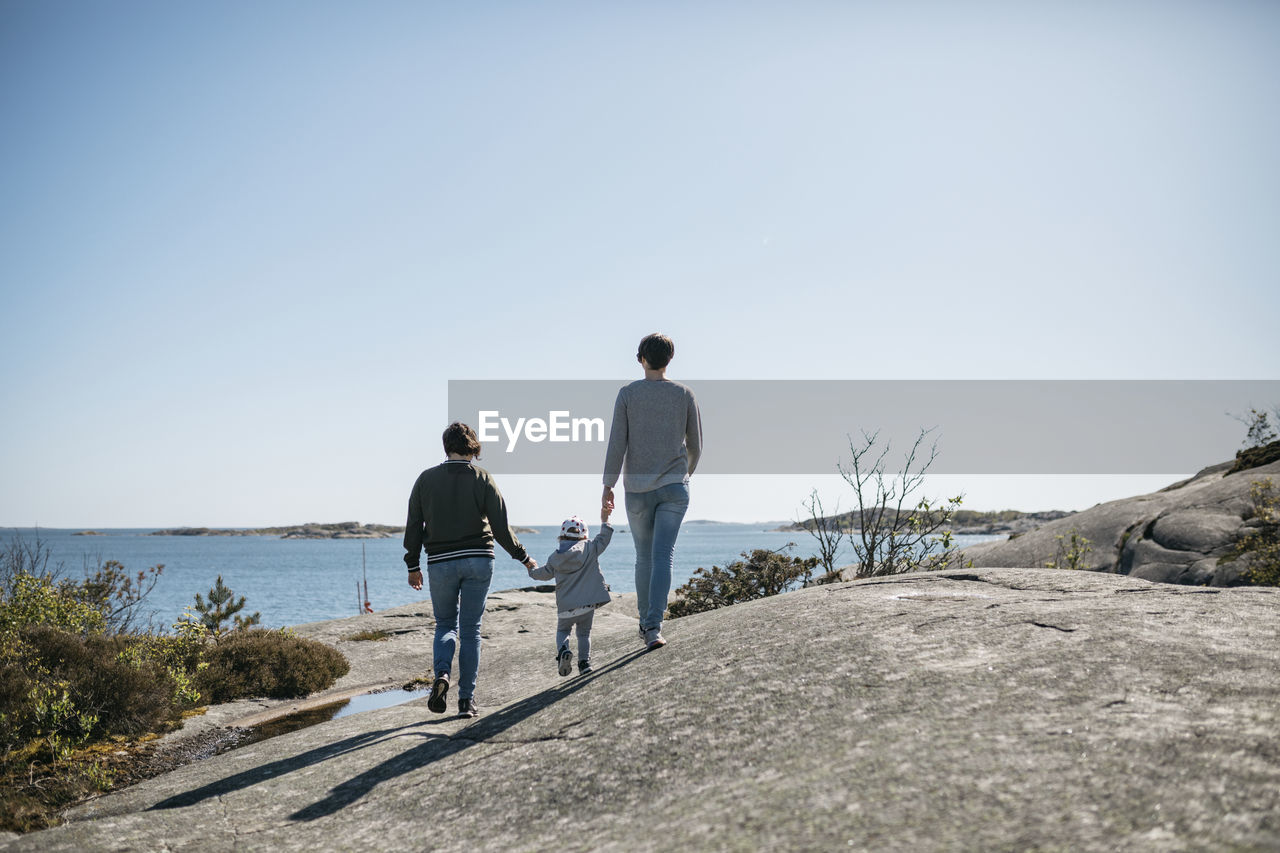 Mothers walking with daughter on coast