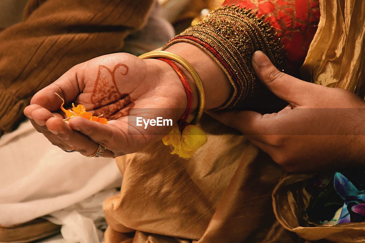 Cropped hand of groom holding petal during wedding ceremony