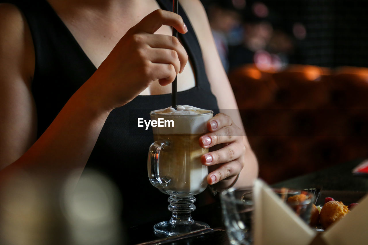 Close-up of woman holding glass at bar