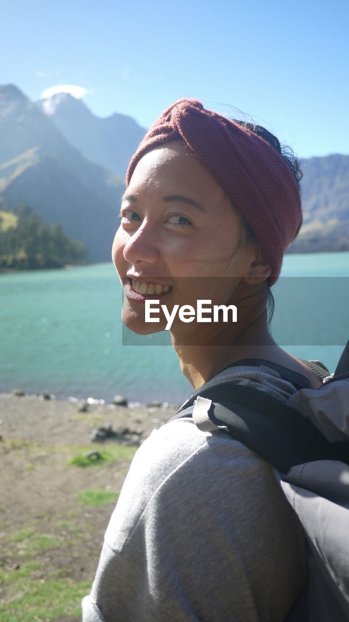 PORTRAIT OF YOUNG WOMAN AGAINST LAKE