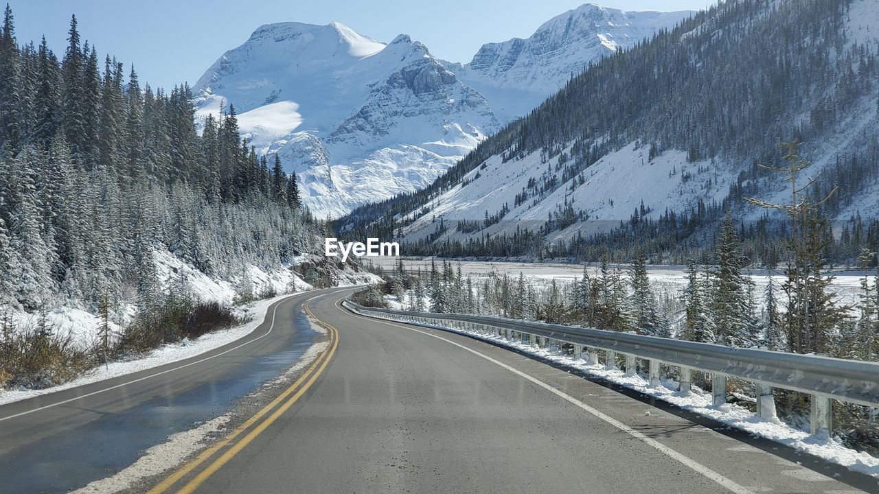 Road by snowcapped mountains during winter