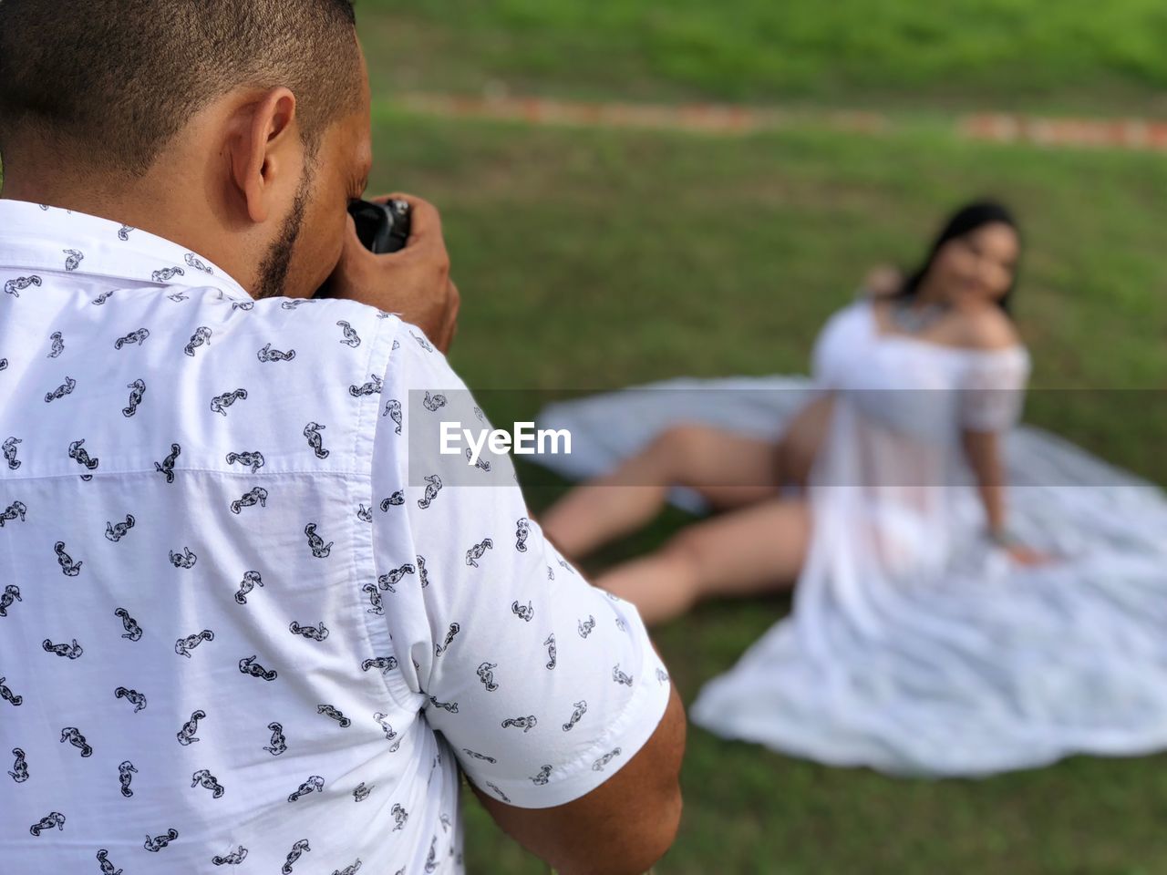 Man photographing pregnant woman on field