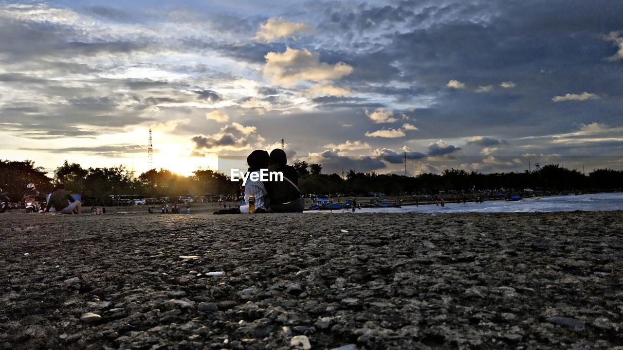 rear view of woman standing on beach against sky during sunset