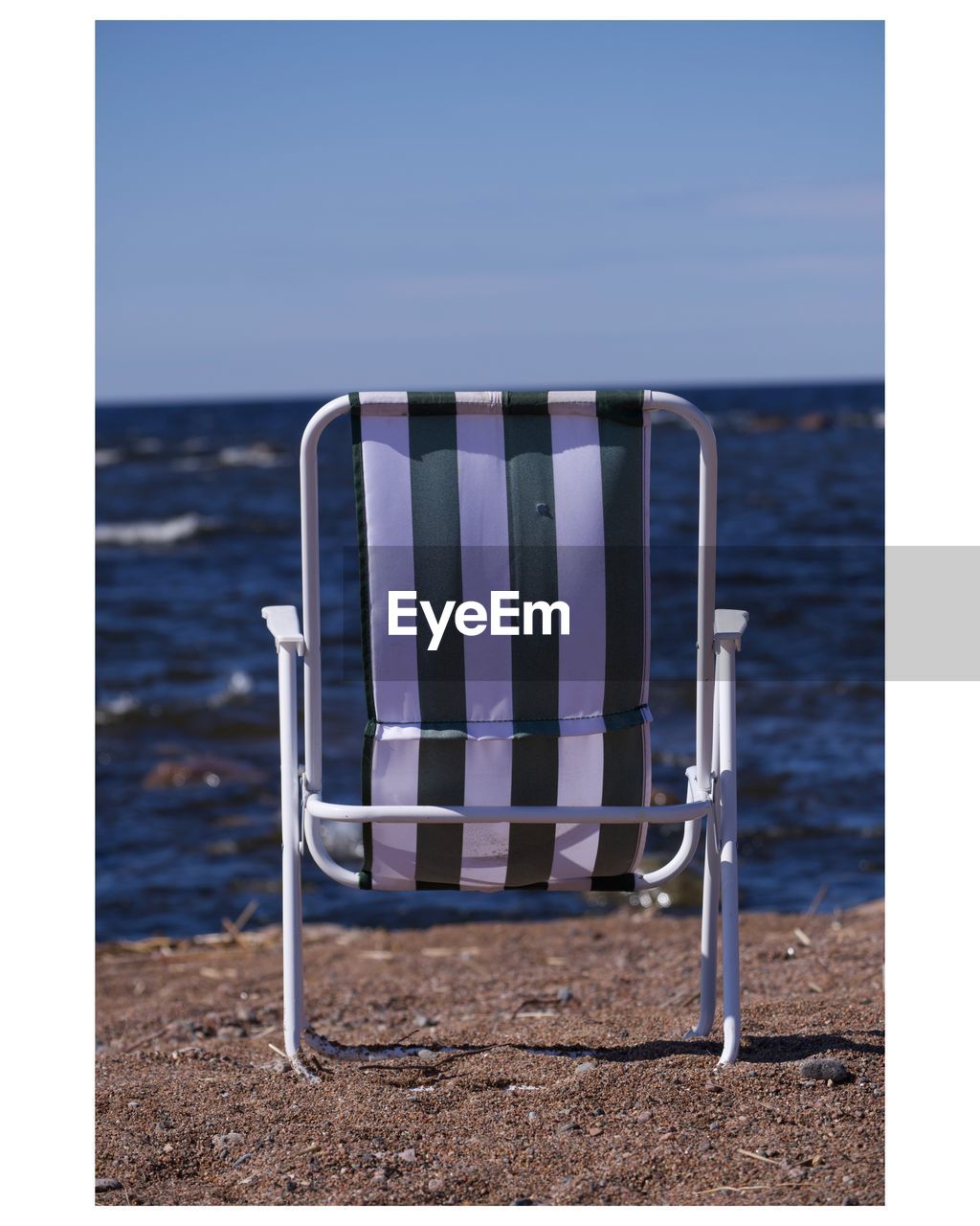 Empty chairs on beach against clear sky