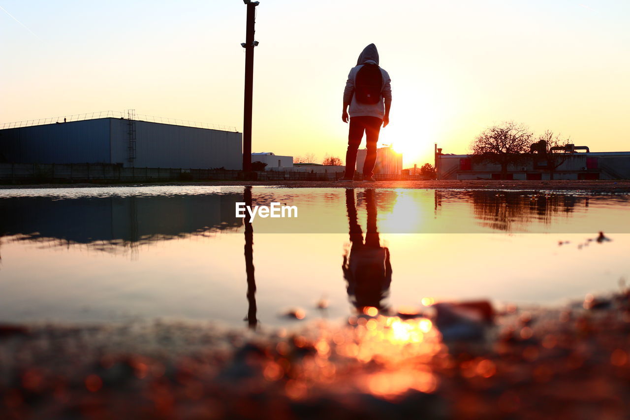 Reflection in puddle in city during sunset