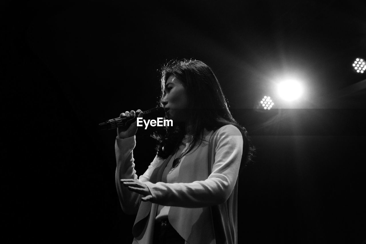 Low angle view of woman with microphone singing in concert