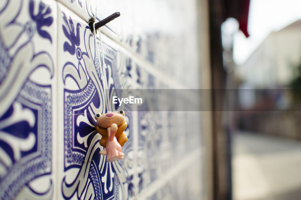 Close-up of angel figurine hanging on tiled wall