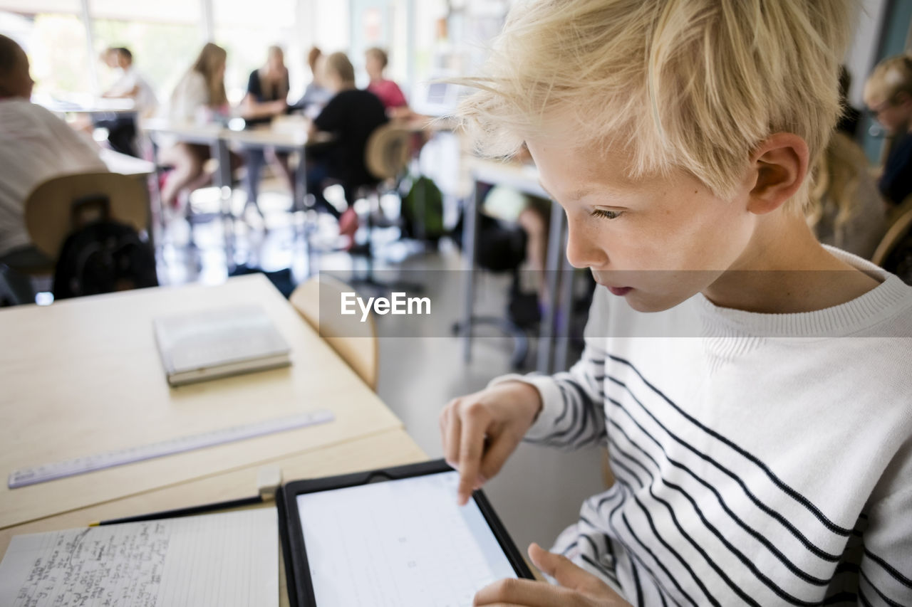 Boy using digital tablet at desk in classroom