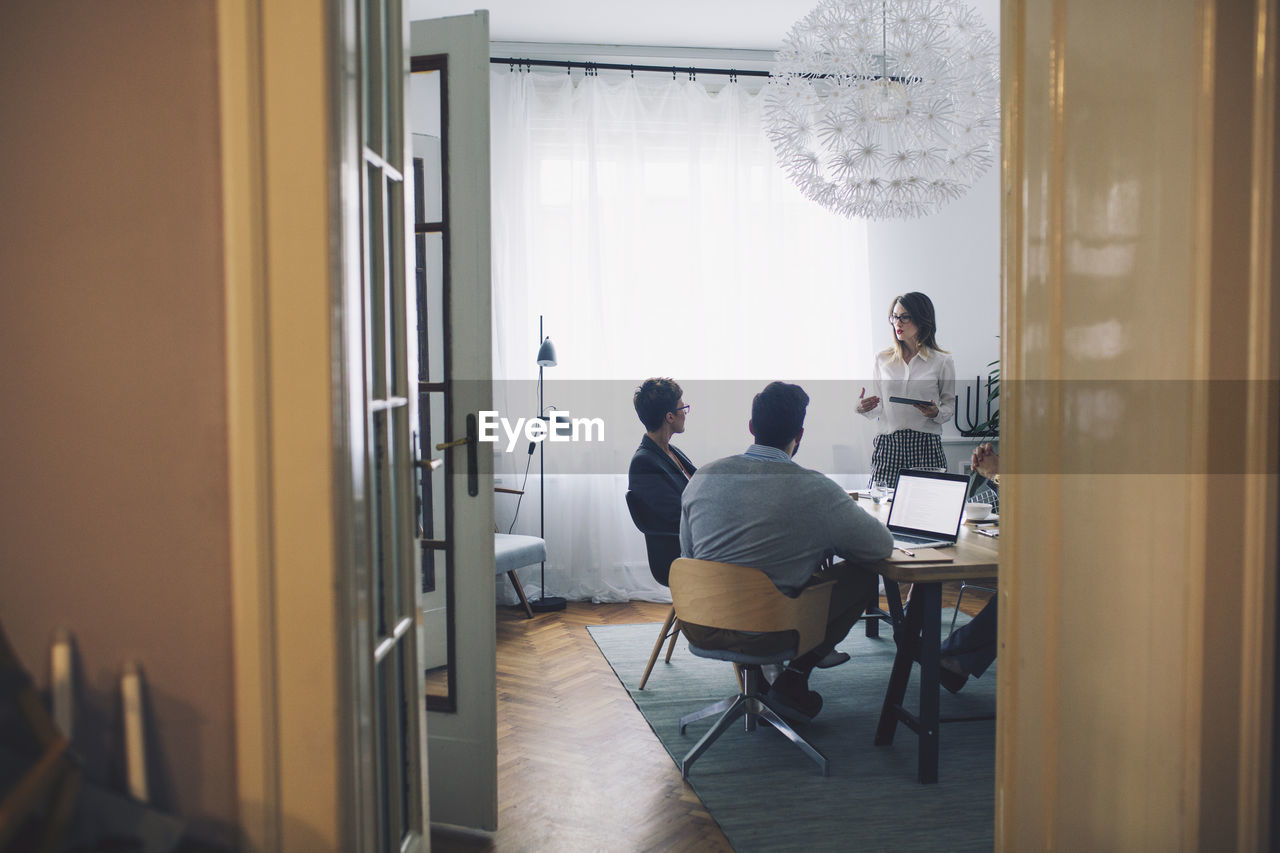 Business people discussing in office seen through doorway