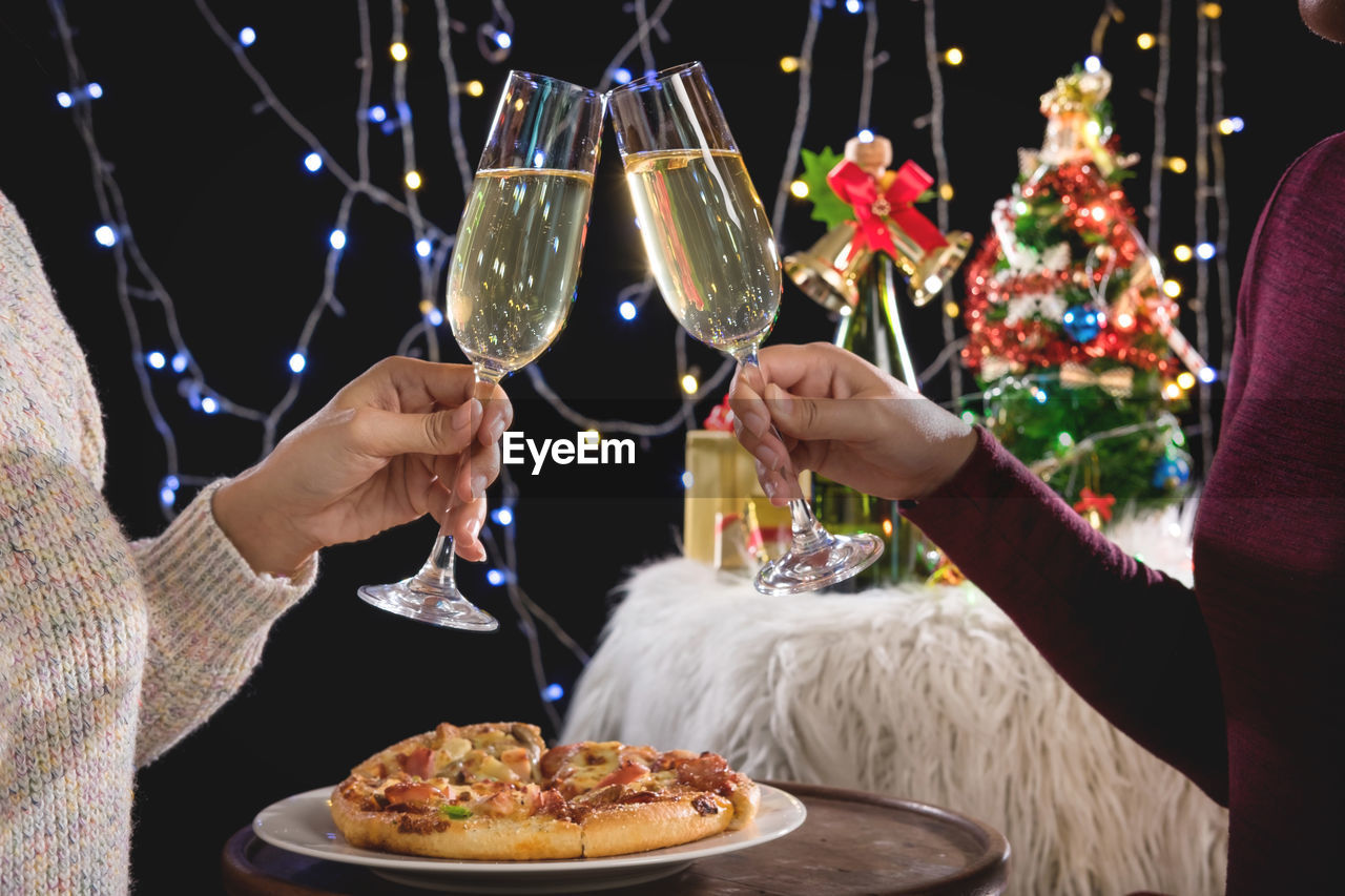 Midsection of friends toasting champagne flute during christmas