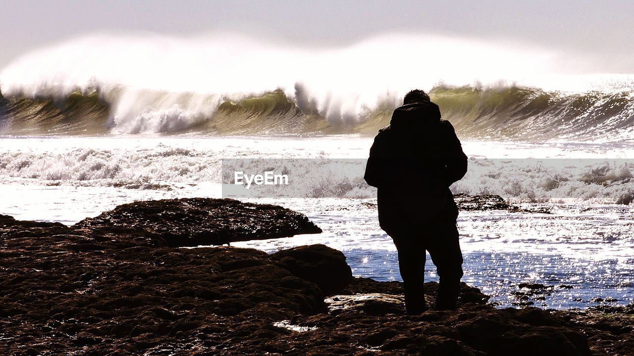 Rear view of man standing against sea