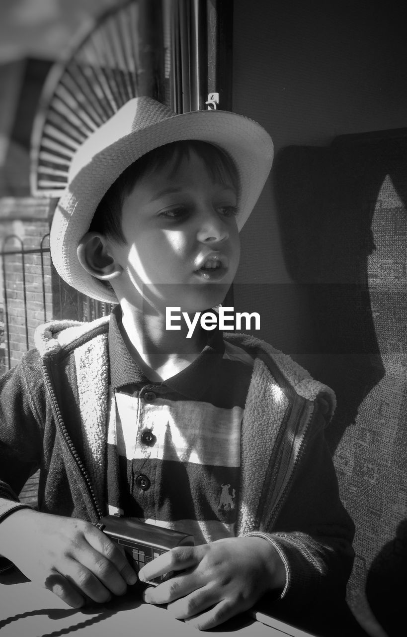 Boy wearing hat looking away in train