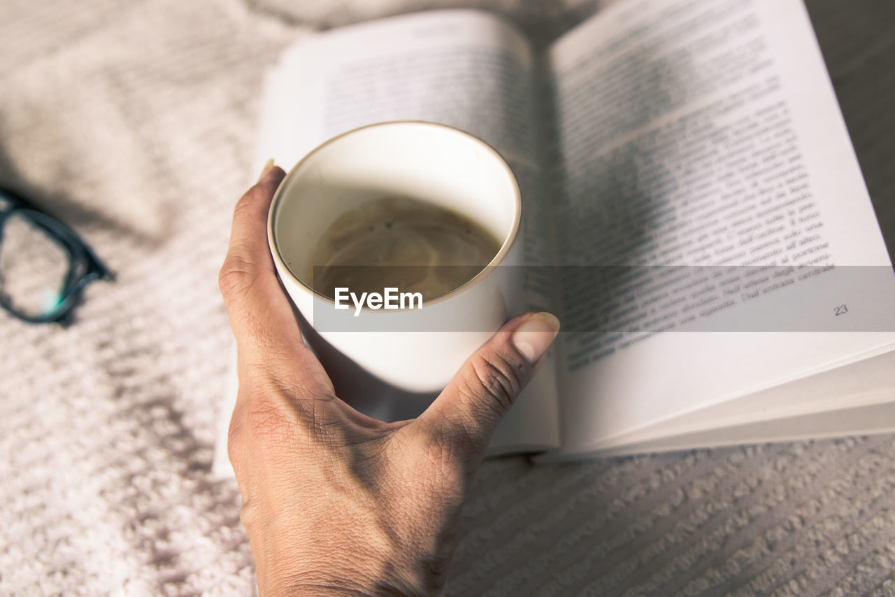 cropped hand of woman holding coffee at table