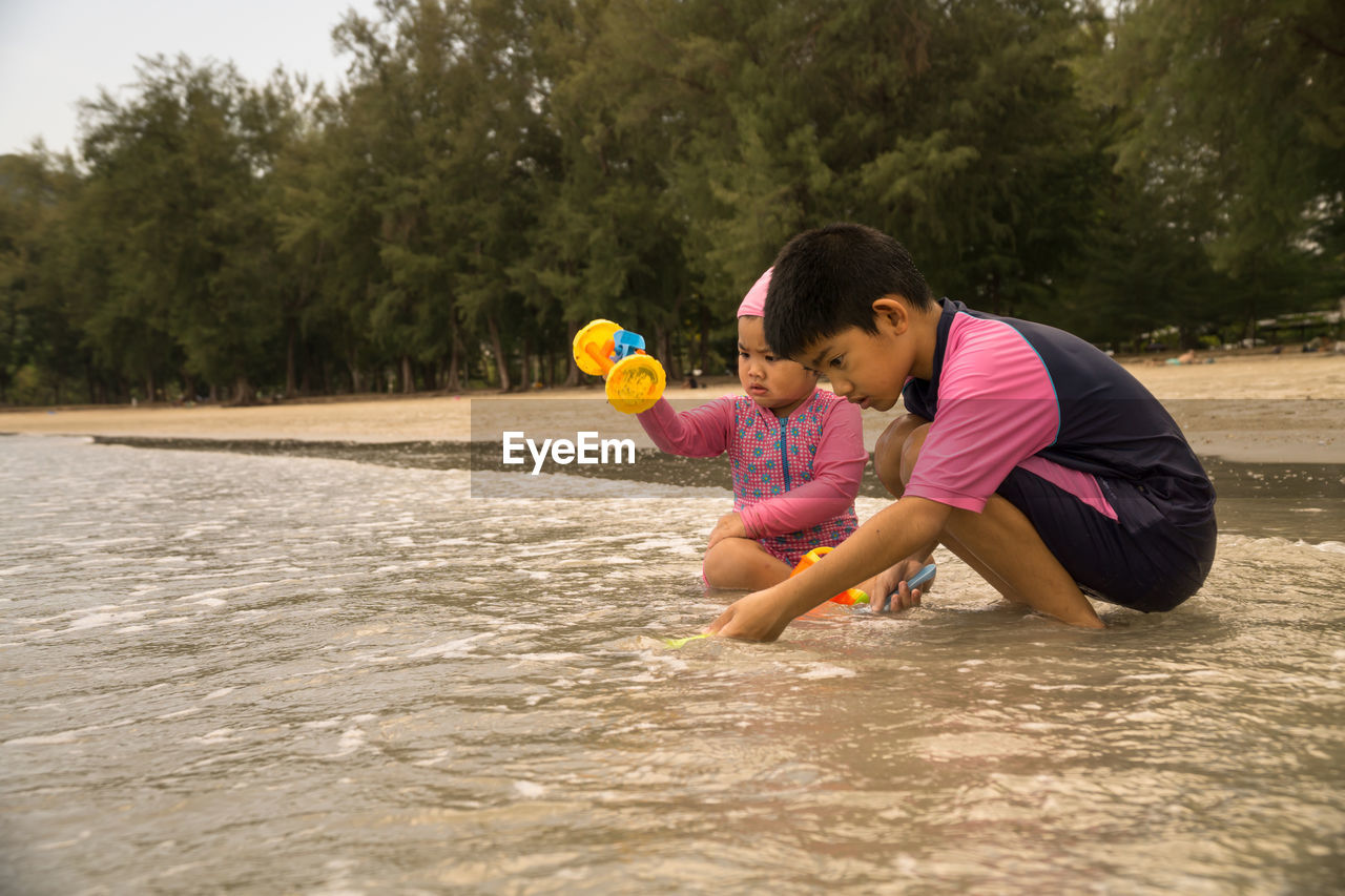 CUTE BOY PLAYING WITH TOY IN WATER