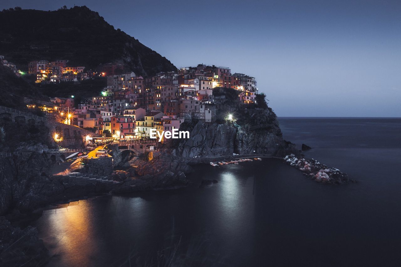 Buildings by sea in vernazza at night
