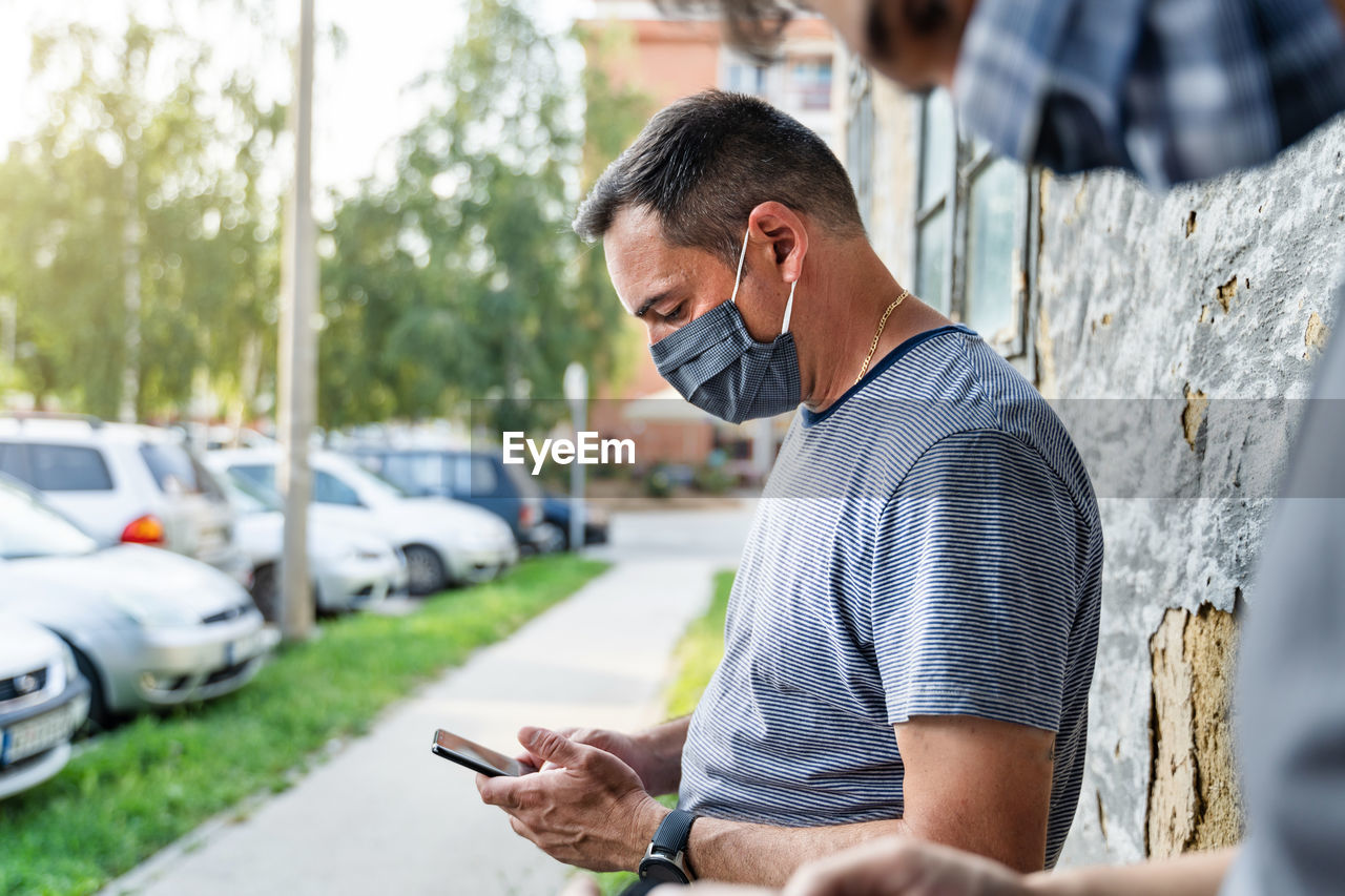 REAR VIEW OF MAN HOLDING MOBILE PHONE