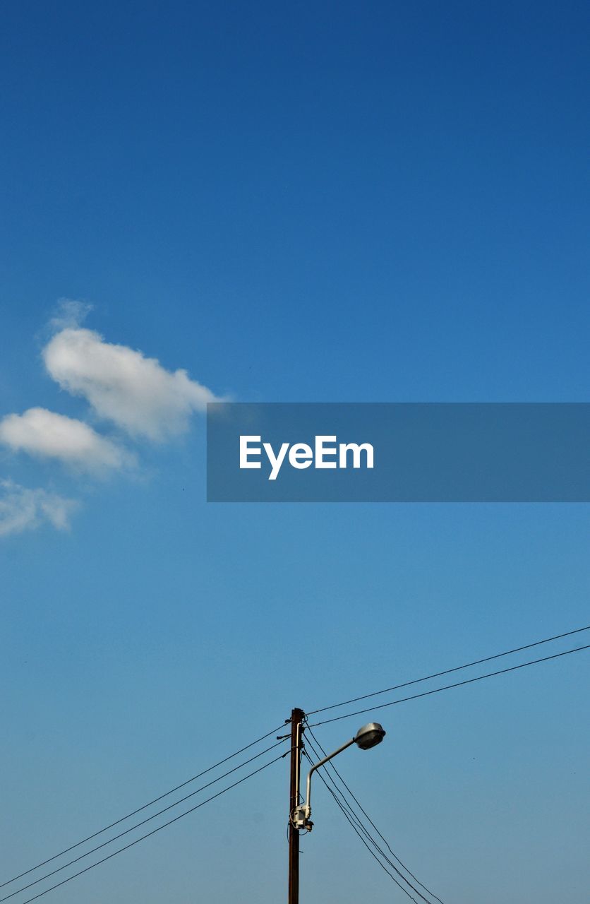 Low angle view of electricity pylon against blue sky