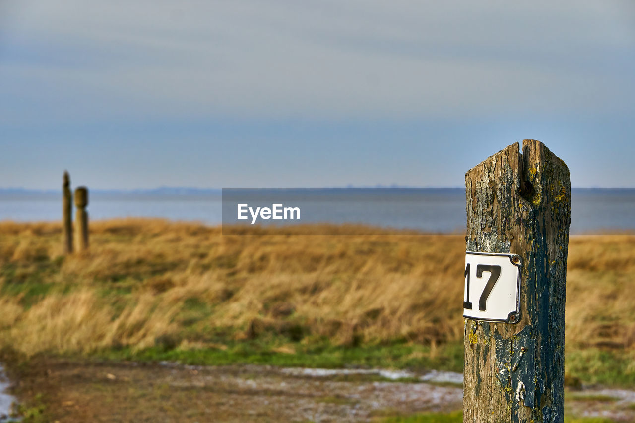 Wooden post on field against sky