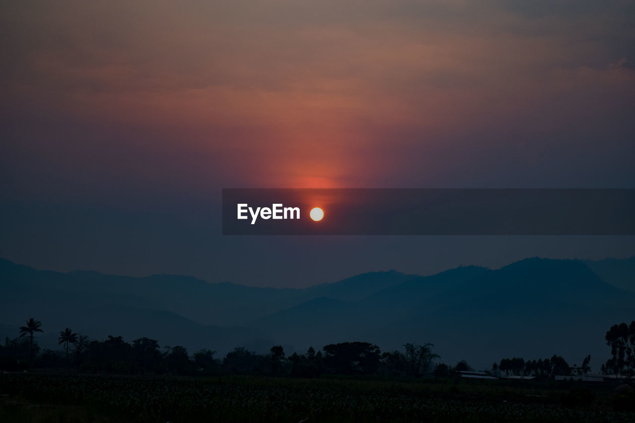 SCENIC VIEW OF SILHOUETTE FIELD AGAINST ORANGE SKY