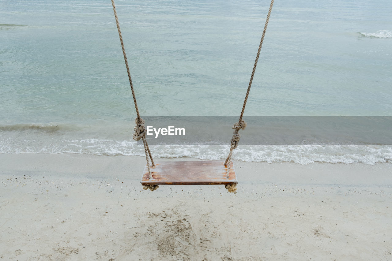 HIGH ANGLE VIEW OF SWING ON SAND AT BEACH