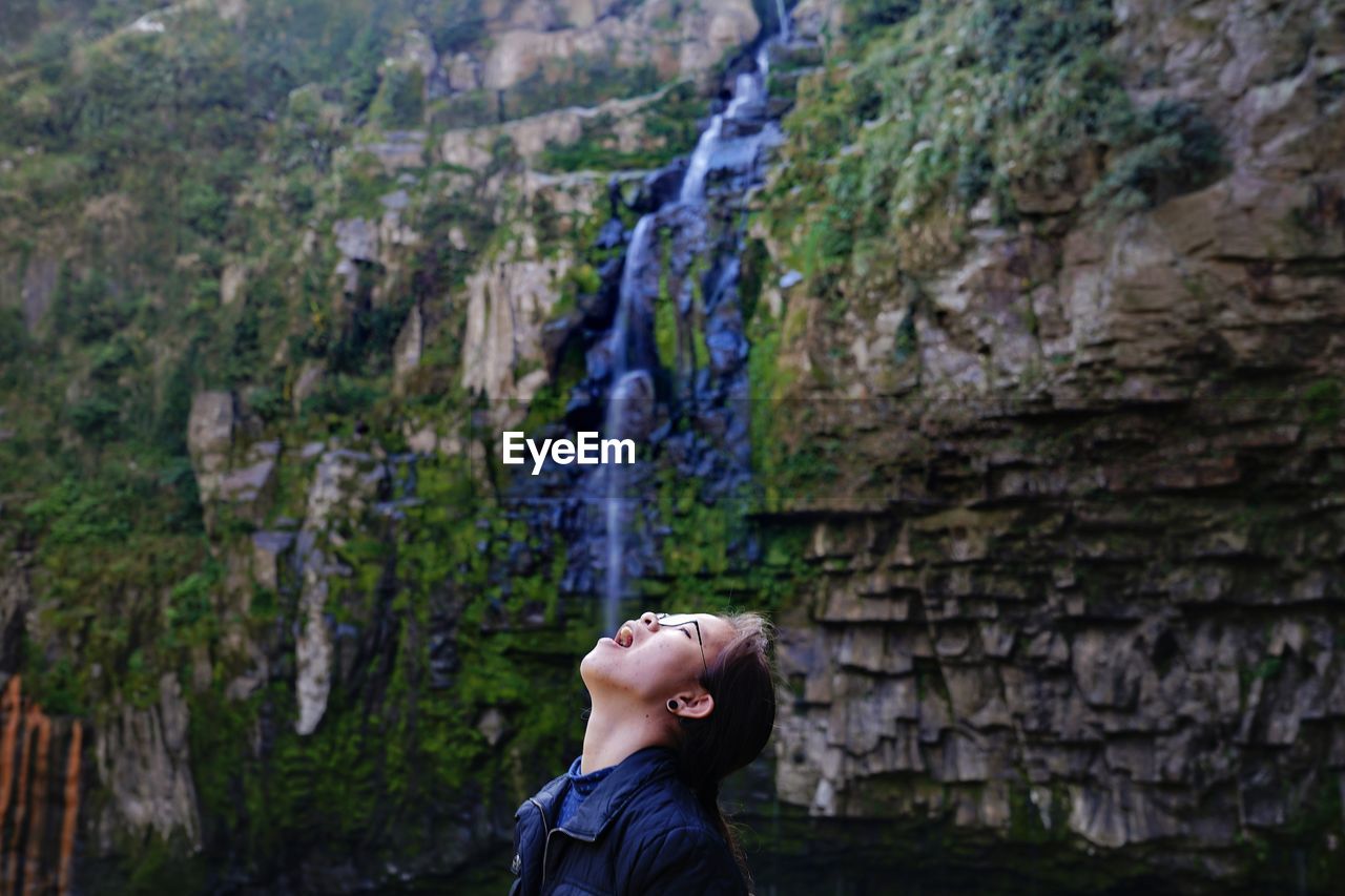 Side view of girl looking up rock