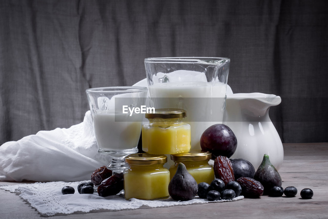 Milk and fruits with containers on textile at table