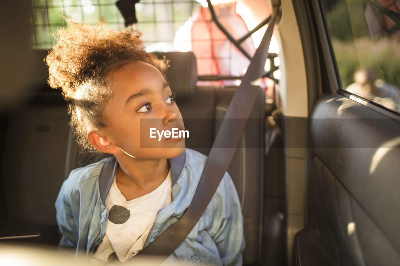 Girl looking through window while sitting in electric car