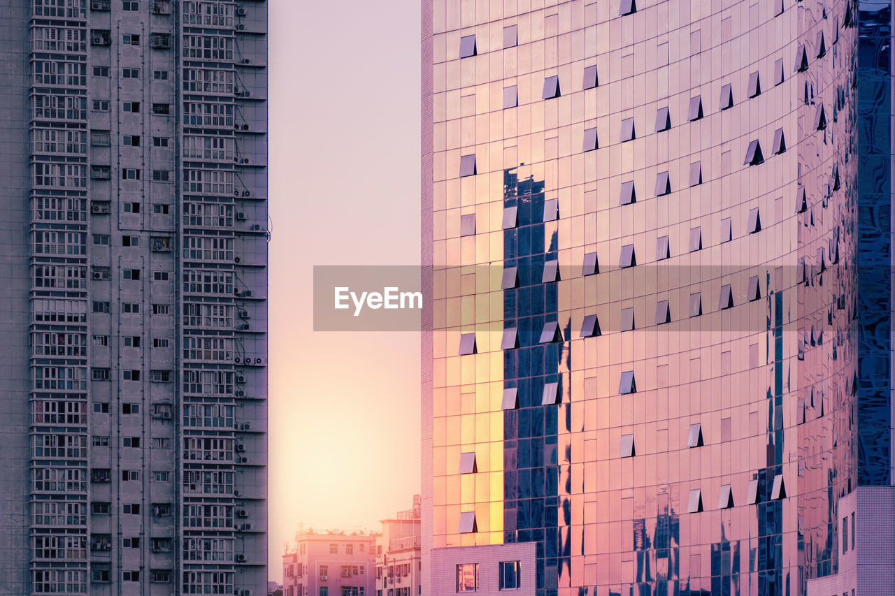Luxury corporate building at sunset against the background of a gray shabby residential building. 