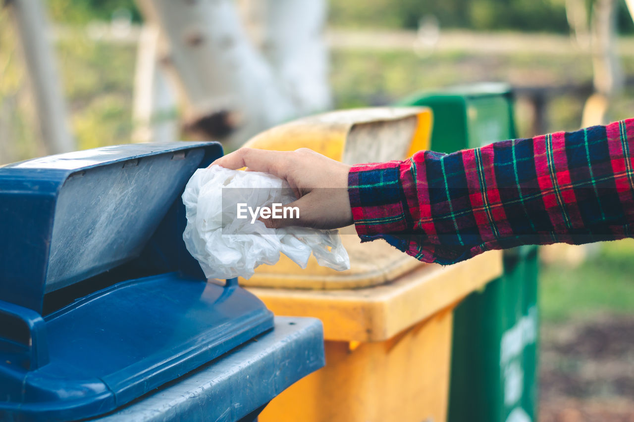 Cropped hand of person throwing garbage in bin