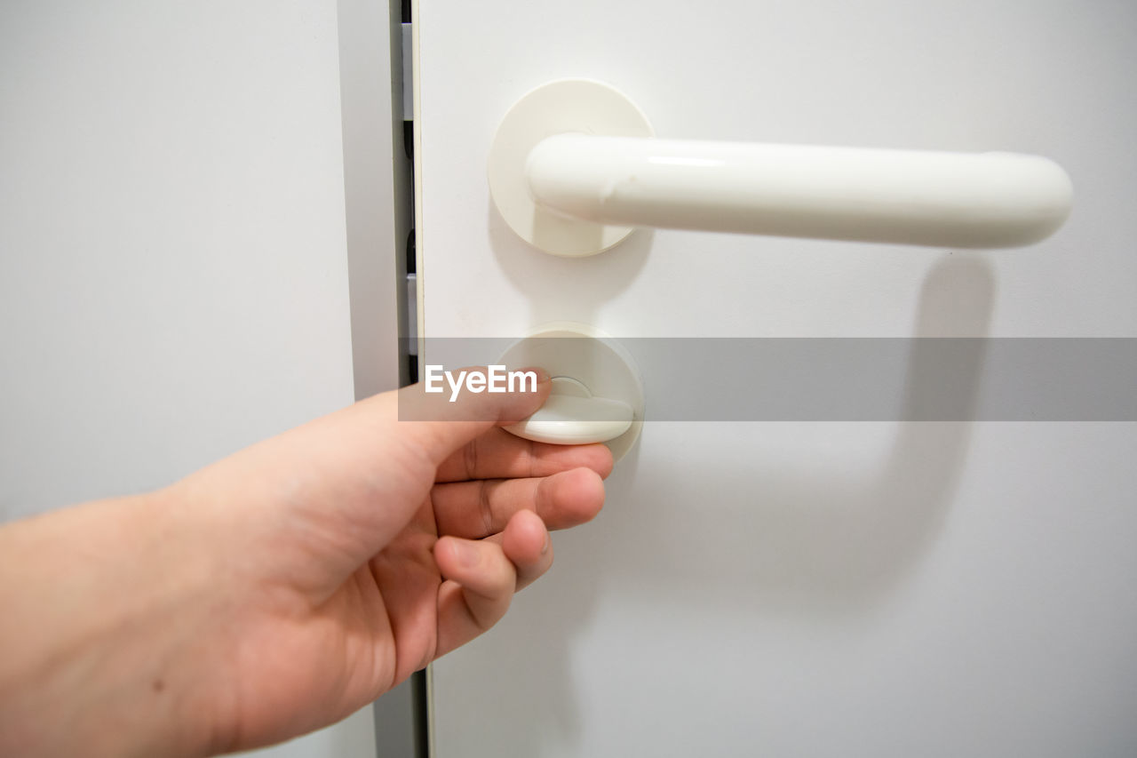 Human hand close doorknob of public restroom door to have privacy inside the cabin 