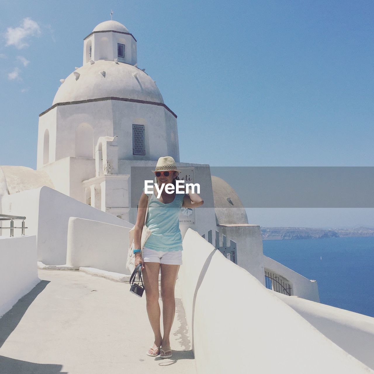 Full length of happy woman standing against built structure at santorini