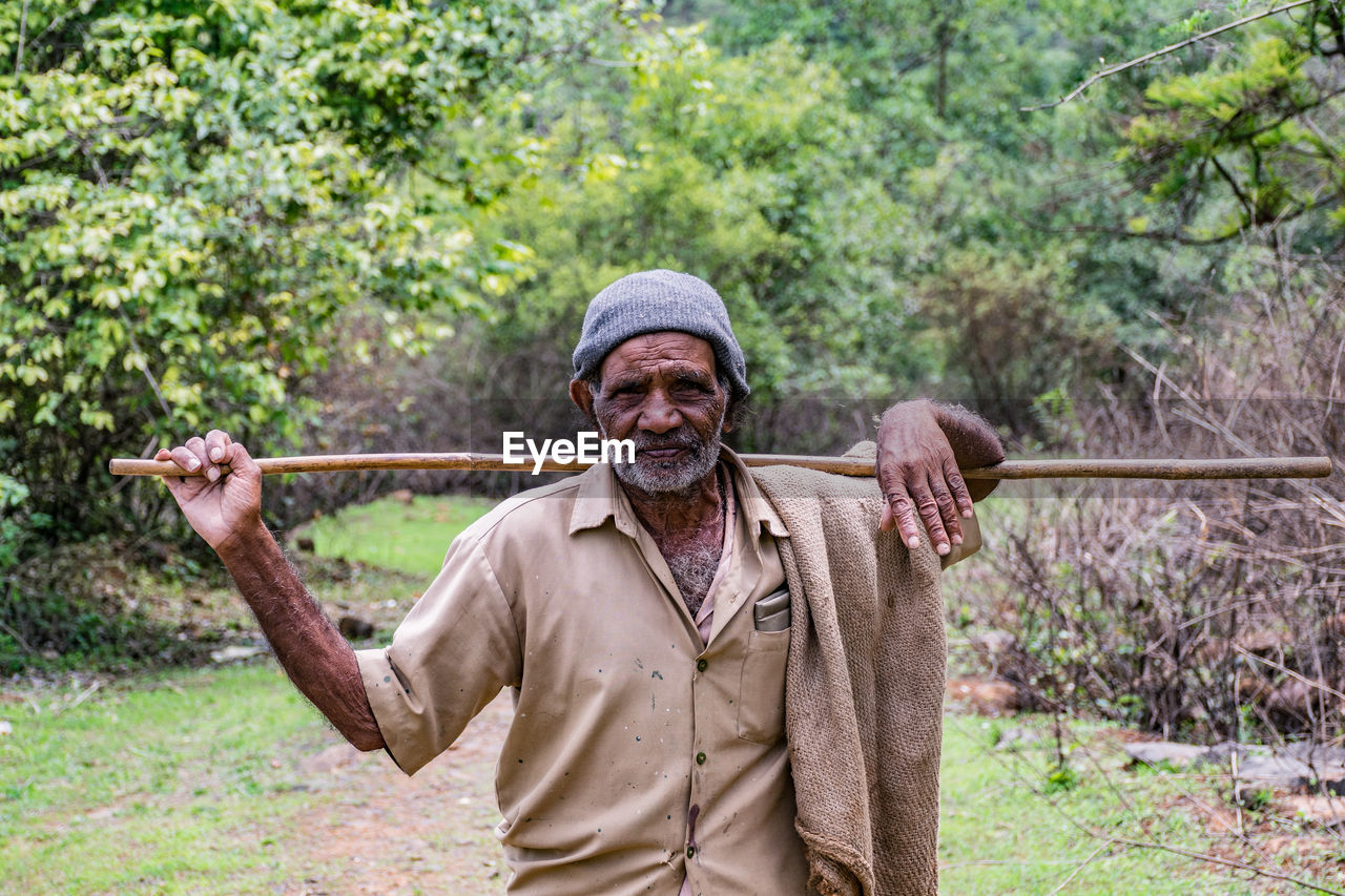 Portrait of senior man holding stick on land