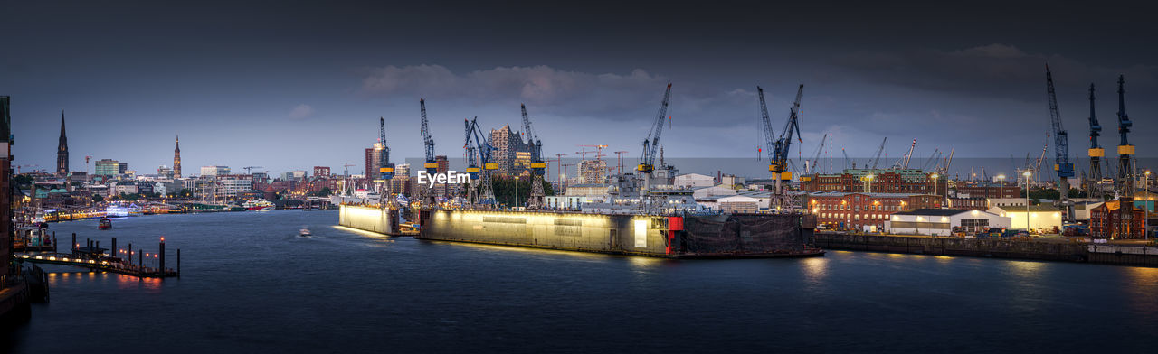 Panoramic view of illuminated commercial dock against sky