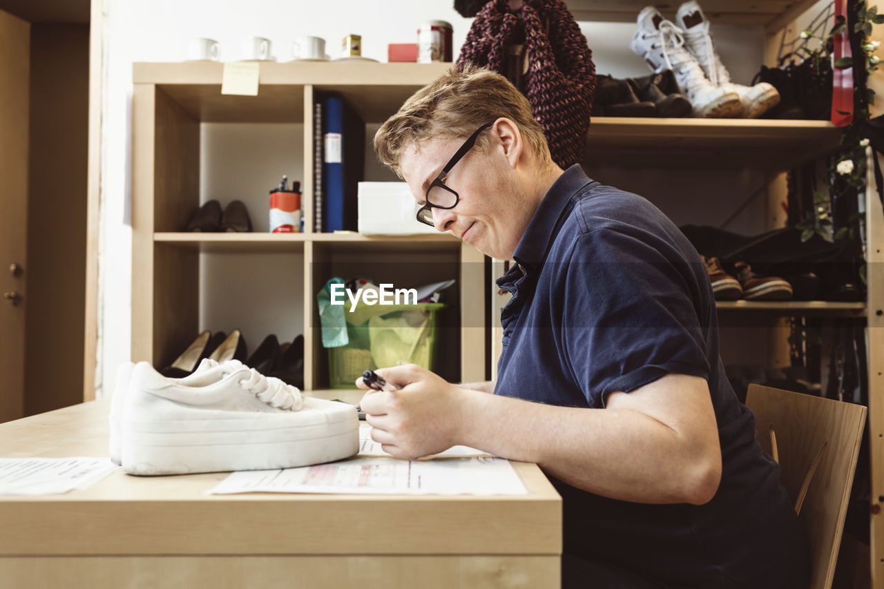 Cashier writing on table while calculating in clothing store