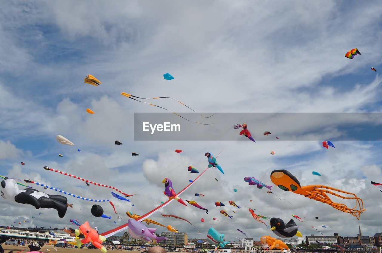 Low angle view of kites flying against sky