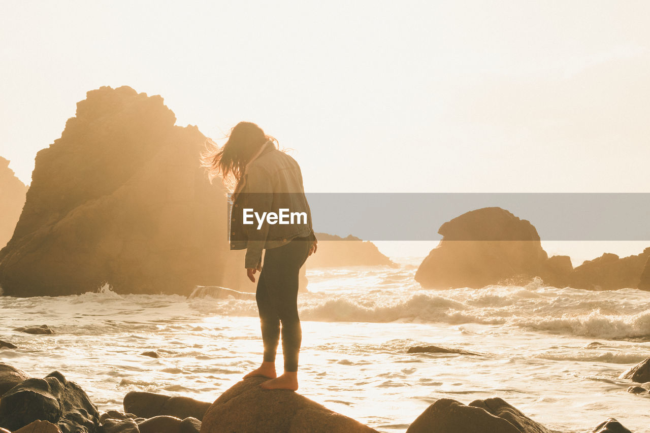 Woman on beach against sky during sunset