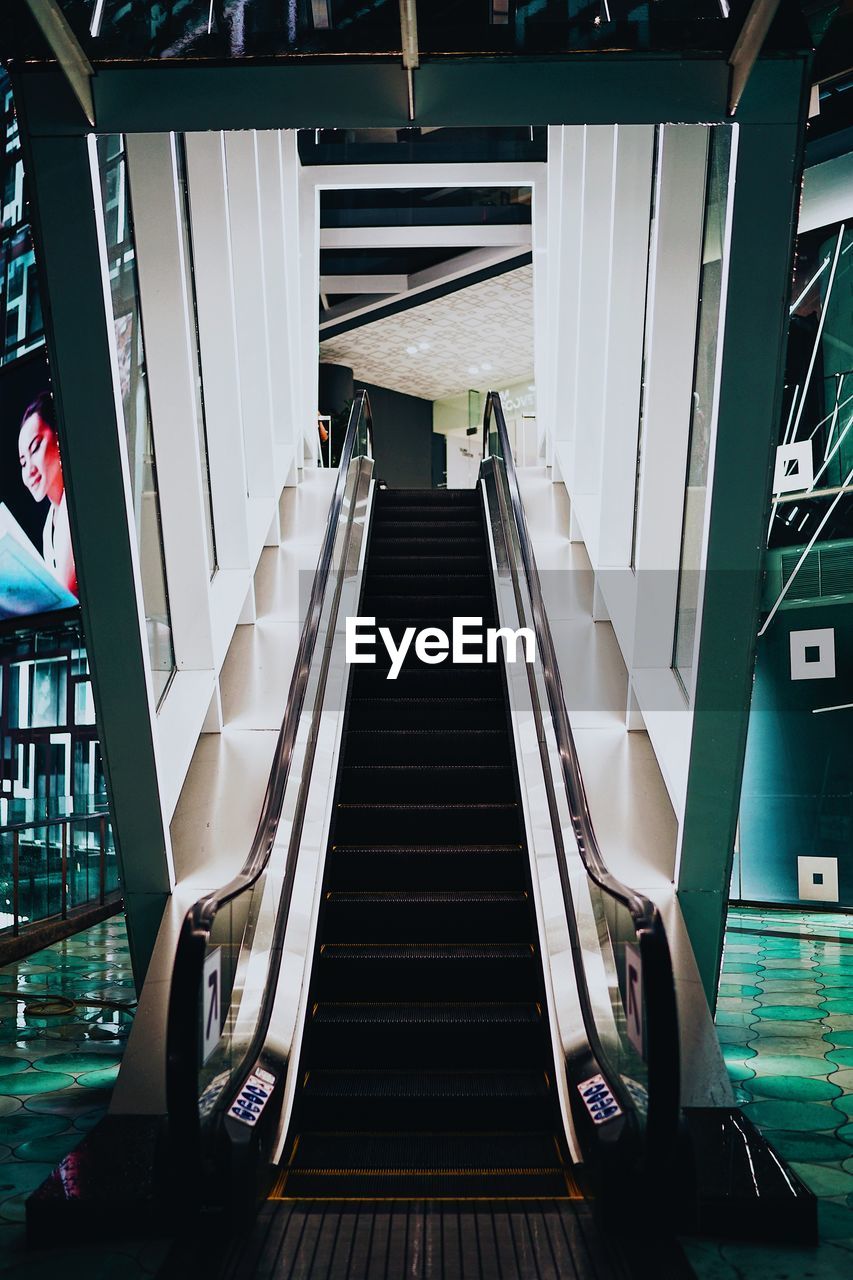 HIGH ANGLE VIEW OF ESCALATOR IN EMPTY STAIRCASE